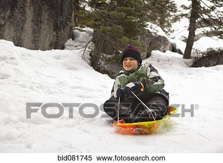 Smiling Hispanic boy riding sled in snow View Large Photo Image Stock Photography - Smiling Hispanic boy riding sled in snow. Fotosearch