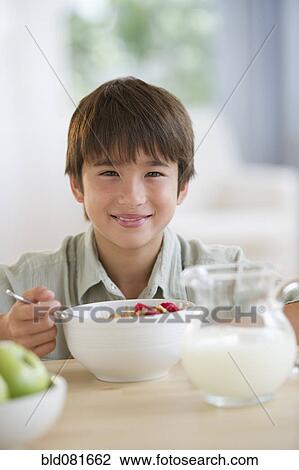 Smiling mixed race boy eating cereal at table View Large Photo Image Stock Image - Smiling mixed race boy eating cereal at table. Fotosearch
