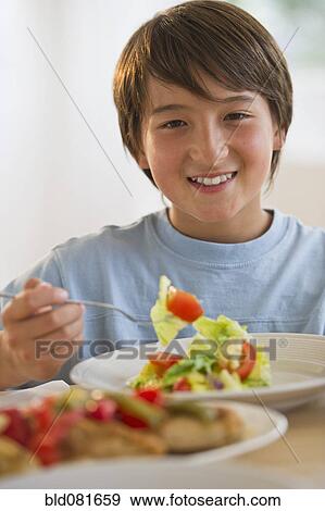 Stock Photo - Smiling mixed race boy eating salad. Fotosearch