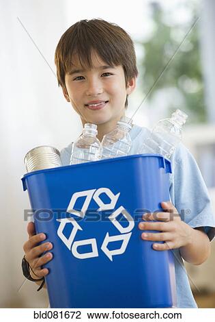 Stock Image - Smiling mixed race boy holding recycling bin. Fotosearch