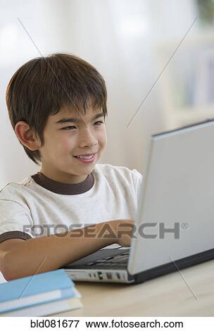 Stock Photo - Smiling mixed race boy using laptop. Fotosearch