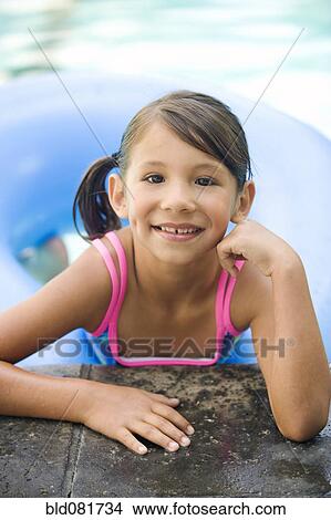 Smiling mixed race girl leaning on edge of swimming pool View Large Photo Image Picture - Smiling mixed race girl leaning on edge of swimming pool. Fotosearch