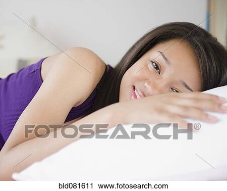 Smiling mixed race teenage girl laying on pillow View Large Photo Image Stock Image - Smiling mixed race teenage girl laying on pillow. Fotosearch