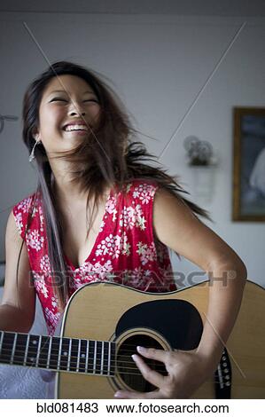 Smiling mixed race teenage girl playing guitar View Large Photo Image Stock Image - Smiling mixed race teenage girl playing guitar. Fotosearch