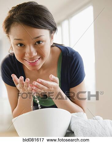 Stock Photo - Smiling mixed race teenage girl washing face. Fotosearch
