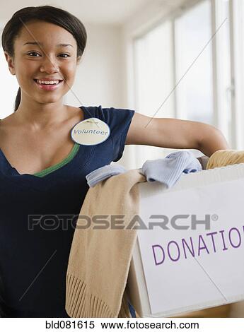Smiling mixed race teenage girl wearing 'Volunteer' pin and holding box of donations View Large Photo Image Stock Photography - Smiling mixed race teenage girl wearing 'Volunteer' pin and holding box of donations. Fotosearch