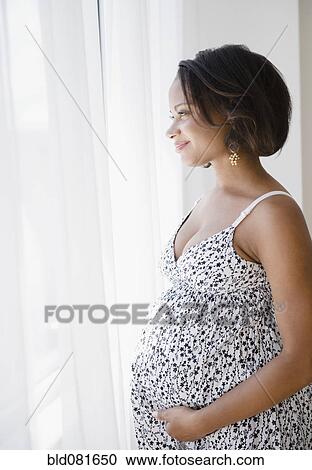 Smiling pregnant Black woman looking out window View Large Photo Image Stock Image - Smiling pregnant Black woman looking out window. Fotosearch