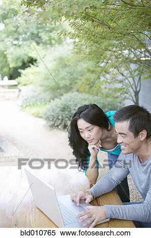 Asian couple using laptop outdoors View Large Photo Image Stock Photography - Asian couple using laptop outdoors. Fotosearch
