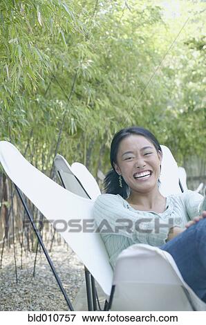 Asian woman sitting outdoors laughing View Large Photo Image Stock Photo - Asian woman sitting outdoors laughing. Fotosearch