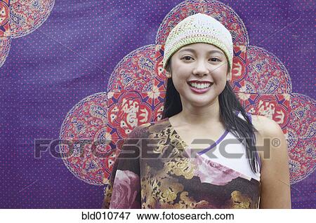 Asian woman smiling in front of tapestry View Large Photo Image Stock Photo - Asian woman smiling in front of tapestry. Fotosearch