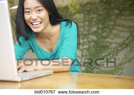 Stock Photo - Asian woman using laptop outdoors. Fotosearch