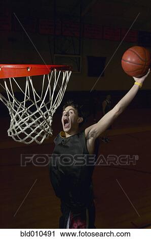 Stock Image - Basketball player about to slam dunk the ball. Fotosearch