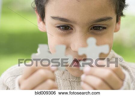 Stock Photograph - Boy fitting puzzle pieces together. Fotosearch