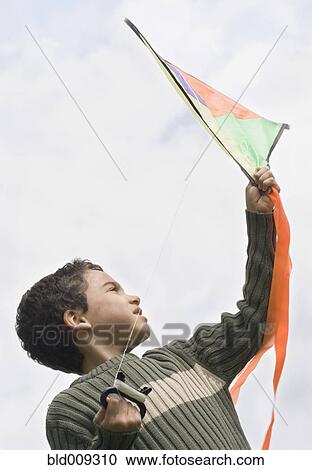 Stock Image - Boy preparing to fly kite. Fotosearch