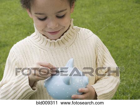 Boy putting money in piggy bank View Large Photo Image Stock Image - Boy putting money in piggy bank. Fotosearch
