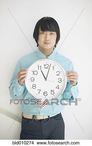 Businessman holding a clock View Large Photo Image Picture - Businessman holding a clock. Fotosearch