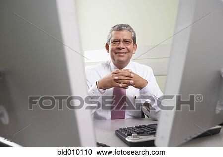 Stock Image - Businessman sitting at desk. Fotosearch