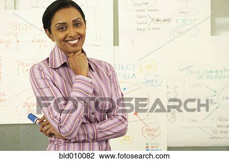 Stock Image - Businesswoman standing in front of charts. Fotosearch