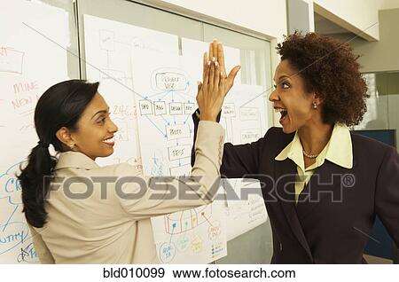 Stock Photo - Businesswomen giving high five. Fotosearch