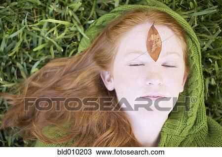 Stock Image - Close up of young woman lying on grass. Fotosearch