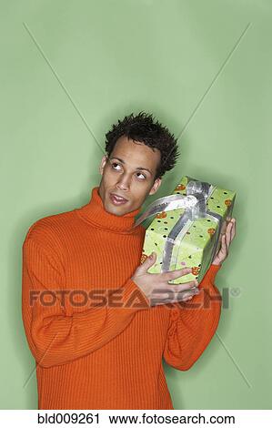 Stock Image - Curious young man with gift. Fotosearch