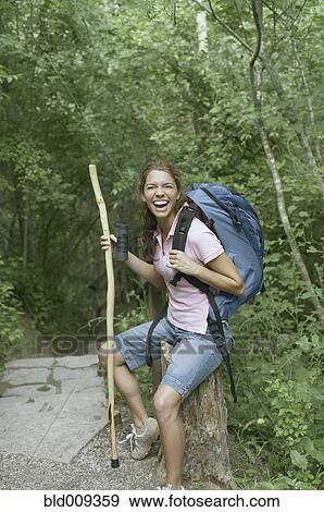 Stock Photo - Female hiker resting on a tree stump . Fotosearch