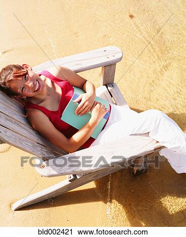 High angle view of a young woman sitting on a beach chair View Large Photo Image Stock Image - High angle view of a young woman sitting on a beach chair. Fotosearch