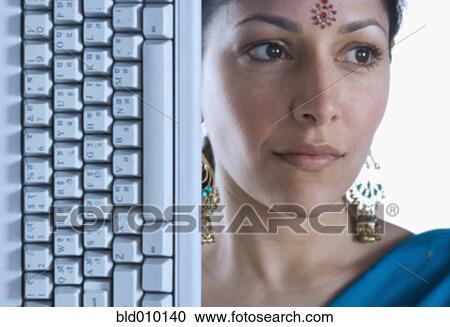 Stock Image - Indian woman wearing bindi next to computer keyboard. Fotosearch