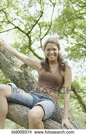 Looking up at a young woman in a tree View Large Photo Image Picture - Looking up at a young woman in a tree. Fotosearch