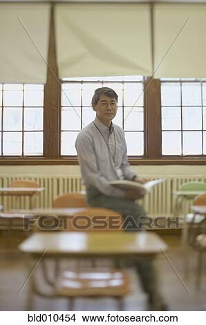 Picture - Male teacher sitting in classroom. Fotosearch