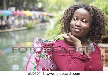 Mid adult woman carrying a shopping bag View Large Photo Image Stock Image - Mid adult woman carrying a shopping bag. Fotosearch