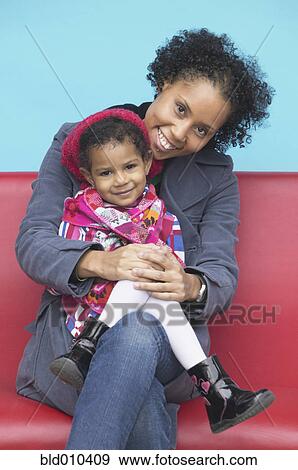 Stock Photo - Portrait of a mother sitting with daughter. Fotosearch