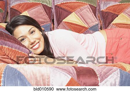 Portrait of a young woman lying on a bed View Large Photo Image Stock Image - Portrait of a young woman lying on a bed. Fotosearch