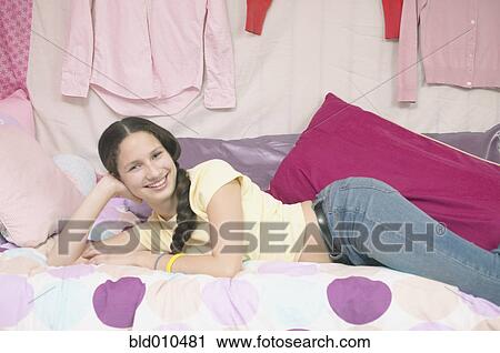 Stock Image - Portrait of teenage girl on bed. Fotosearch