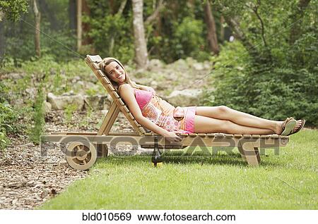 Stock Photo - Portrait of woman lying on lounge chair. Fotosearch
