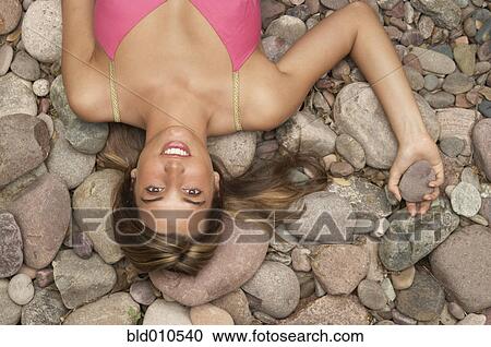Portrait of young woman lying on rocks View Large Photo Image Stock Image - Portrait of young woman lying on rocks. Fotosearch