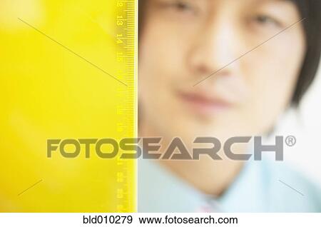 Ruler in front of businessman's face View Large Photo Image Stock Photo - Ruler in front of businessman's face. Fotosearch