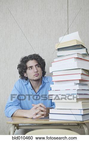 Teenage boy looking at stack of books View Large Photo Image Stock Image - Teenage boy looking at stack of books. Fotosearch