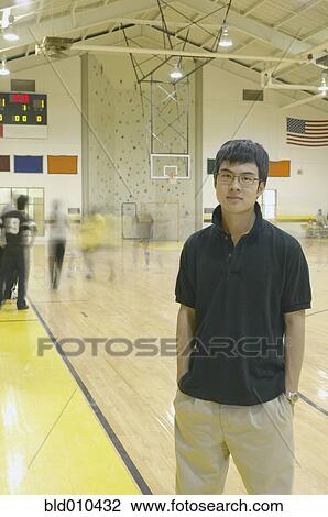 Stock Image - Teenage boy standing on basketball court. Fotosearch