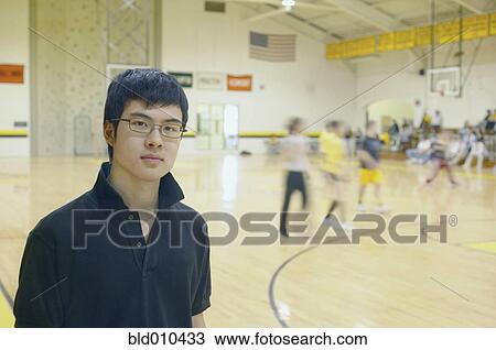 Stock Image - Teenage boy standing on basketball court. Fotosearch