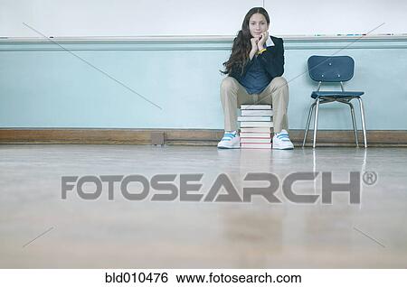 Stock Photograph - Teenage girl sitting on stack of books. Fotosearch