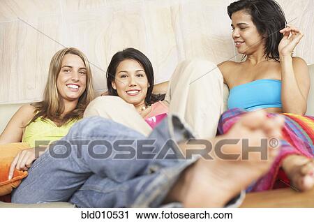 Three young women together on couch View Large Photo Image Stock Image - Three young women together on couch. Fotosearch