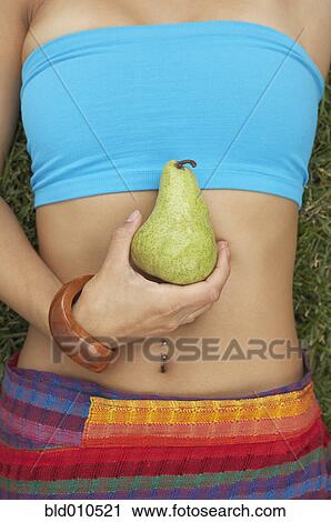 Torso of young woman holding a pear View Large Photo Image Stock Image - Torso of young woman holding a pear. Fotosearch