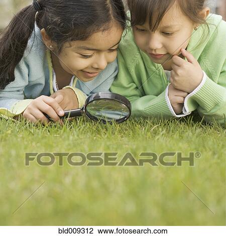 Two girls using a magnifying glass View Large Photo Image Stock Image - Two girls using a magnifying glass. Fotosearch