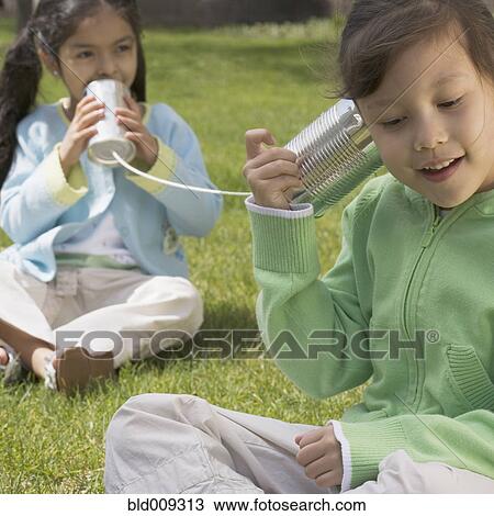 Two girls using tin cans for telephone View Large Photo Image Stock Image - Two girls using tin cans for telephone. Fotosearch