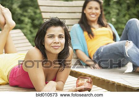 Two women lying on lounge chairs View Large Photo Image Stock Image - Two women lying on lounge chairs. Fotosearch
