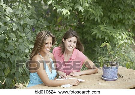 Picture - Two women sitting at picnic table. Fotosearch