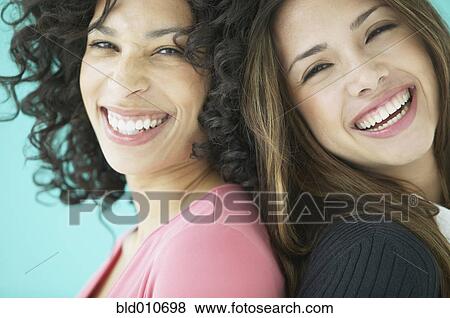 Two women smiling back to back View Large Photo Image Stock Photo - Two women smiling back to back. Fotosearch