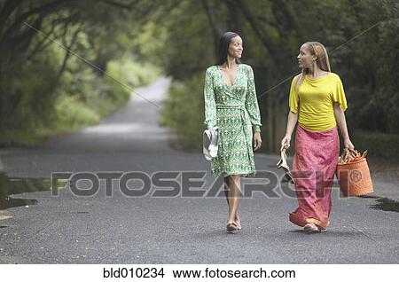 Two women walking on a road View Large Photo Image Picture - Two women walking on a road. Fotosearch