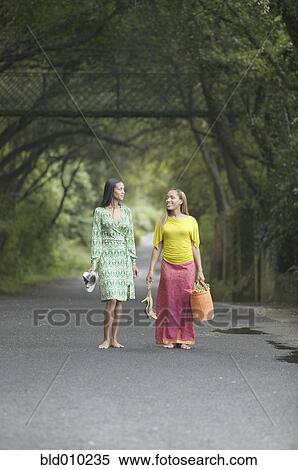 Two women walking on a road View Large Photo Image Stock Photography - Two women walking on a road. Fotosearch